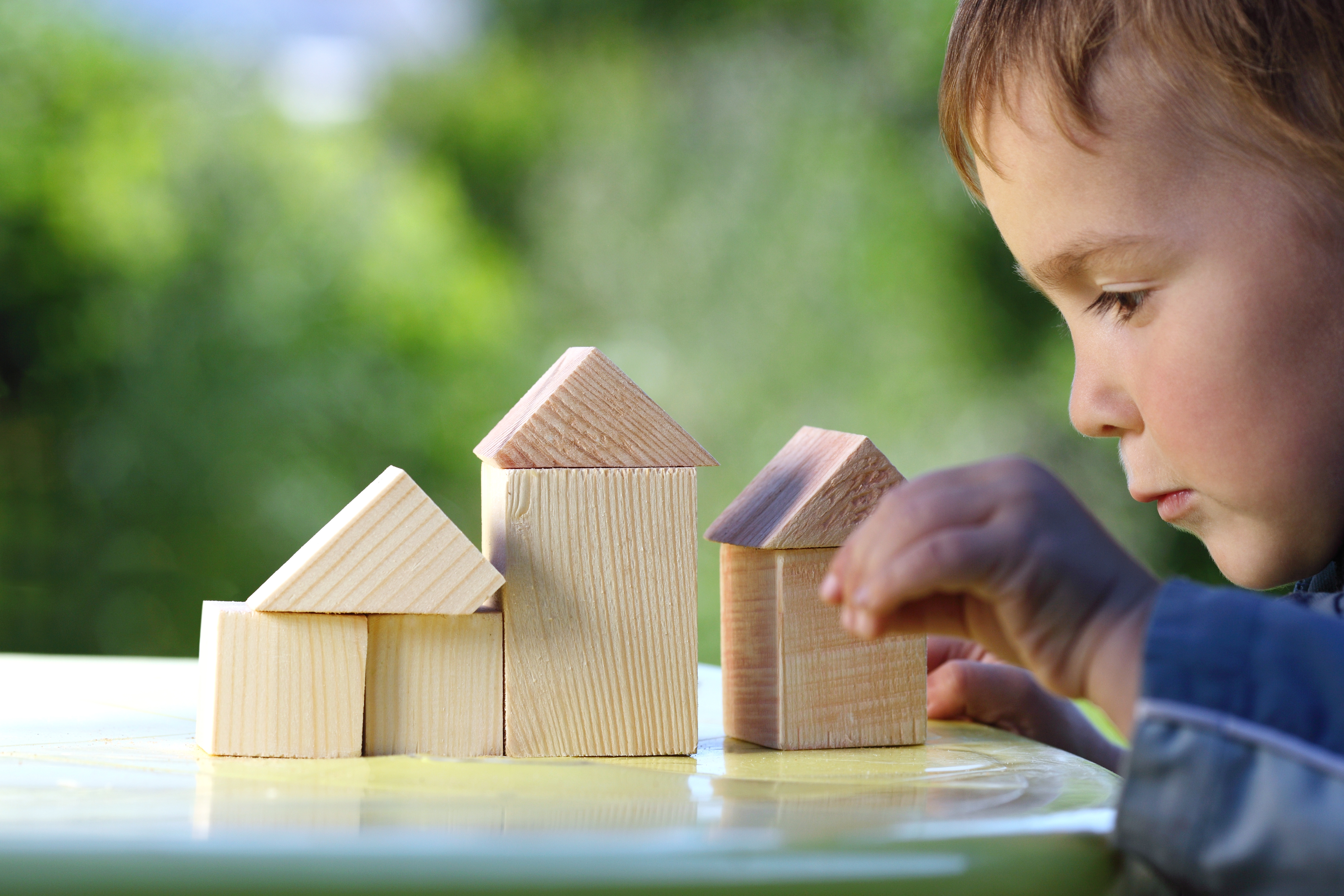 boy raises his hand to the house from wooden cubes/DollarPhotoClub