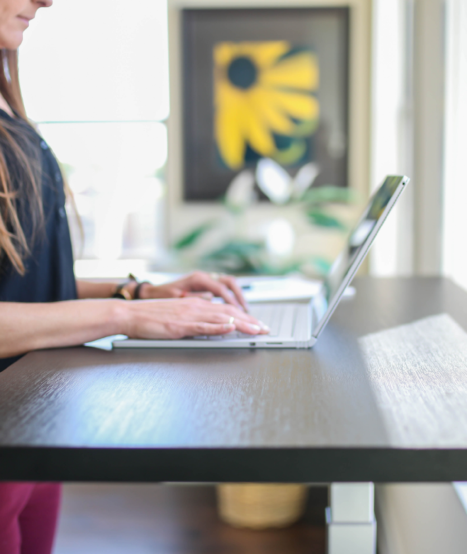 Der Ellenbogenwinkel stimmt. Für einen optimalen Arbeitsplatz am Stehschreibtisch müsste diese Dame allerdings einen zweiten Monitor deutlich höher positionieren. Hierfür gibt es wiederum eigene Schreibtischaufsätze. Fotocredit: © TheStandingDesk/Unsplash